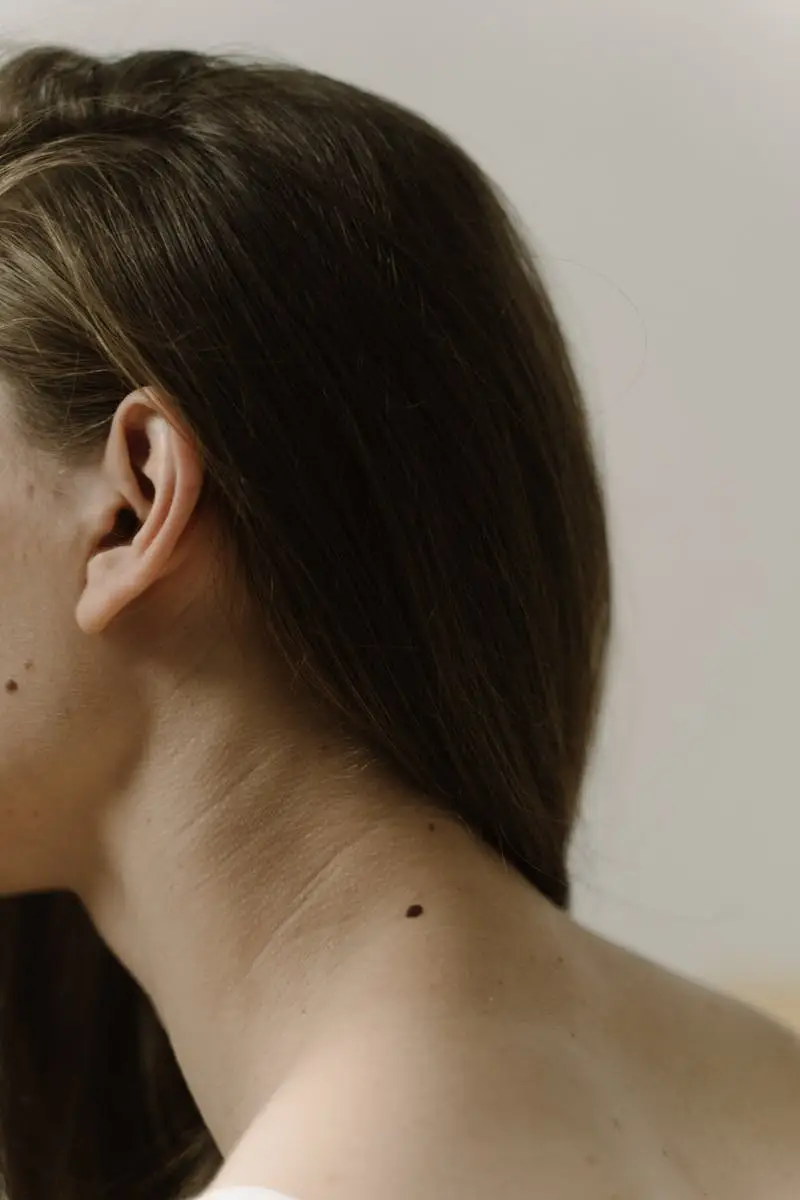 A detailed shot of a woman's neck focusing on a small mole. Minimalist and natural aesthetic.